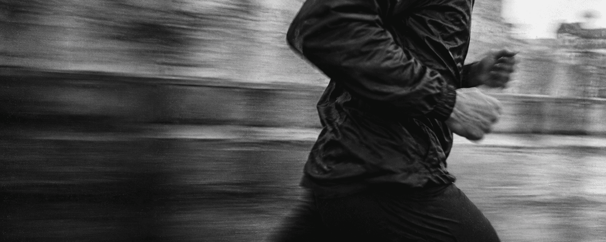 A runner captured in grainy black and white, with the city blurred in motion.